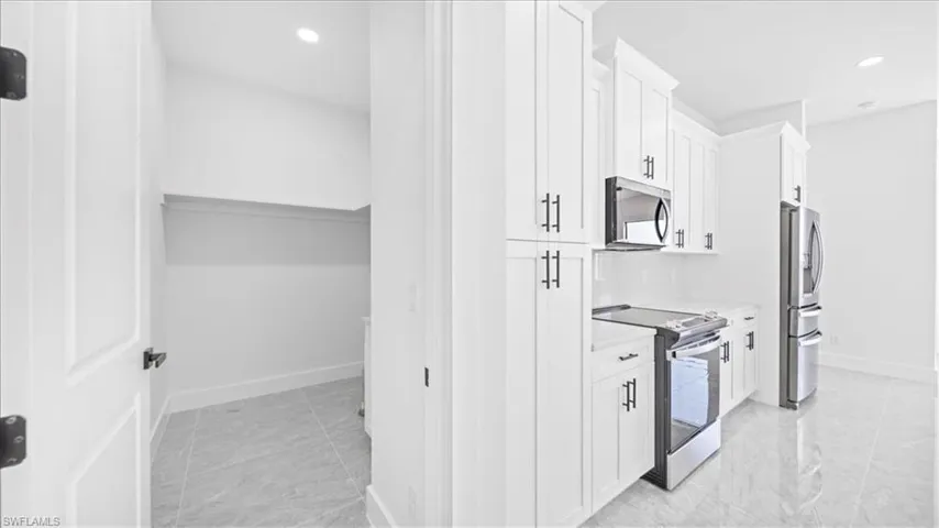 Kitchen with stainless steel appliances, white cabinets, and recessed lighting