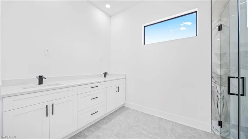 Bathroom featuring double vanity, a marble finish shower, and recessed lighting