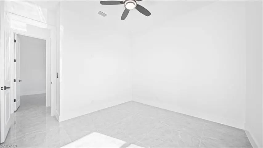 Empty room featuring ceiling fan and baseboards