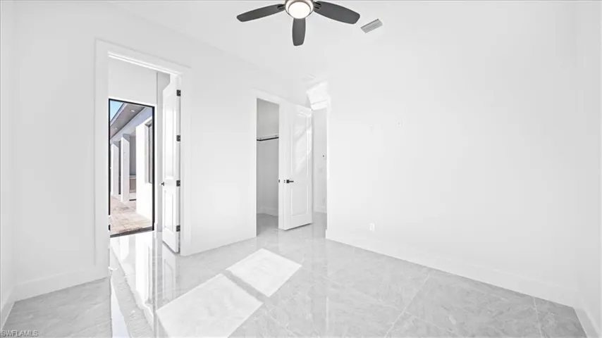 Unfurnished bedroom with a spacious closet and a ceiling fan