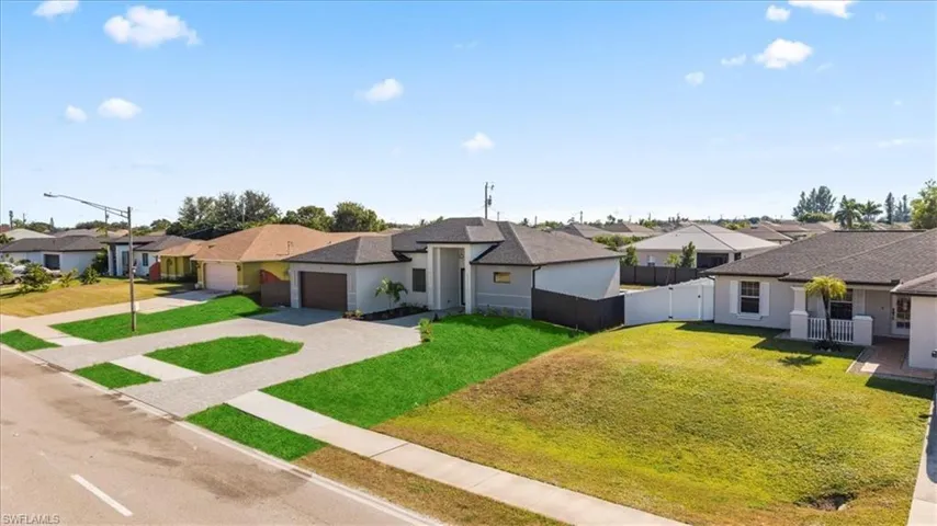 Single story home with a residential view, driveway, stucco siding, a gate, and a garage