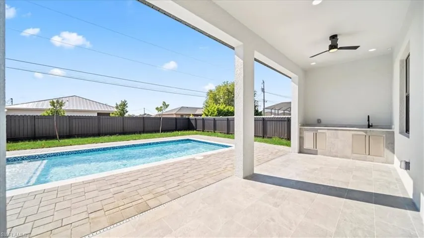 View of swimming pool featuring an outdoor kitchen, patio surround, and a fenced backyard