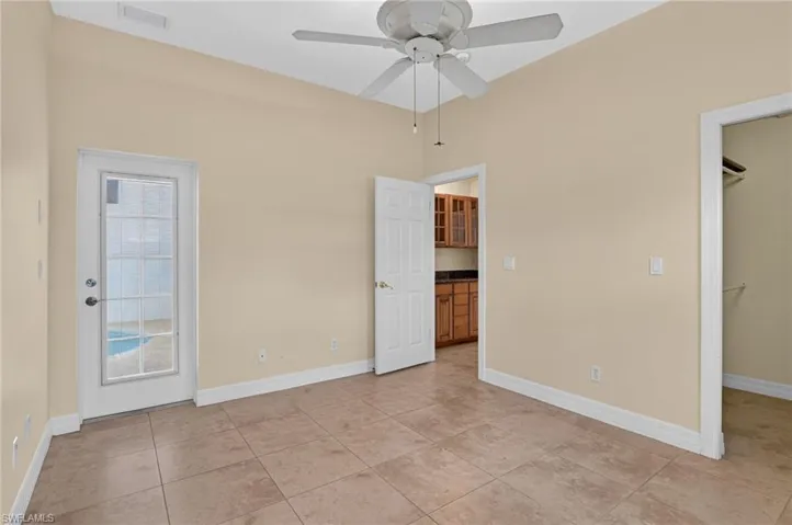 Interior space featuring large-format ceramic tile flooring, a multi-pane glass door, ceiling fan with light fixture, and walk-in closet