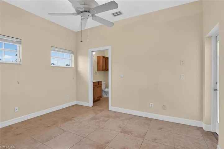 Interior space featuring high ceilings, tile flooring, a white ceiling fan, and multiple windows