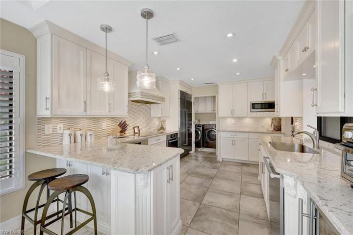 The exquisite custom white cabinetry is crowned w/stunning Cambria gold-veined Quartzite
