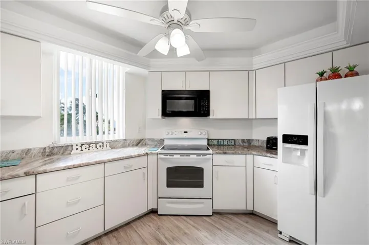 Kitchen featuring white appliances, white cabinets, light wood finished floors, and ceiling fan