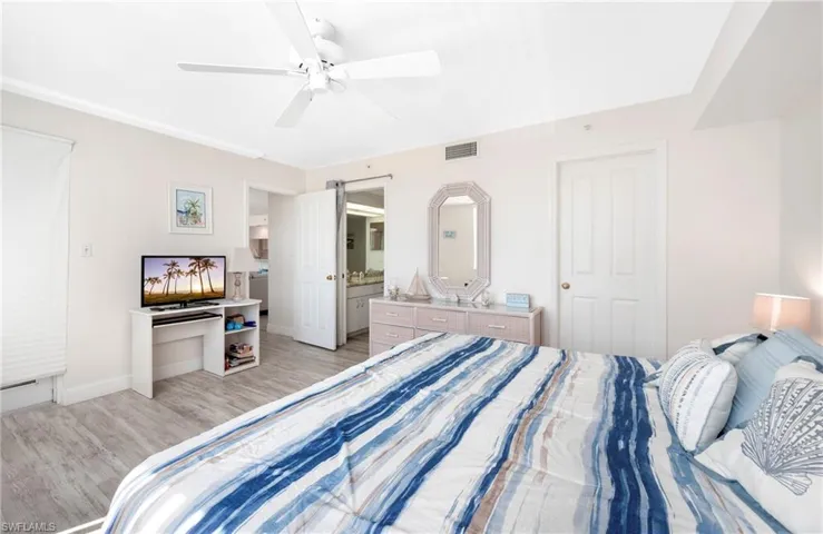 Bedroom with wood finished floors, a ceiling fan, and ensuite bathroom