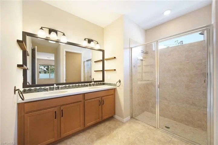 Primary Bathroom  with double vanity, a stall shower, and light tile floors