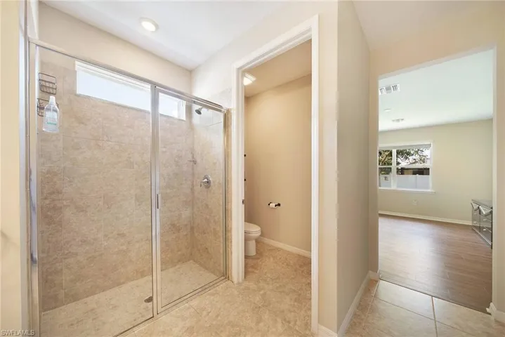 Bathroom featuring healthy amount of natural light, a shower stall, light tile  floors,