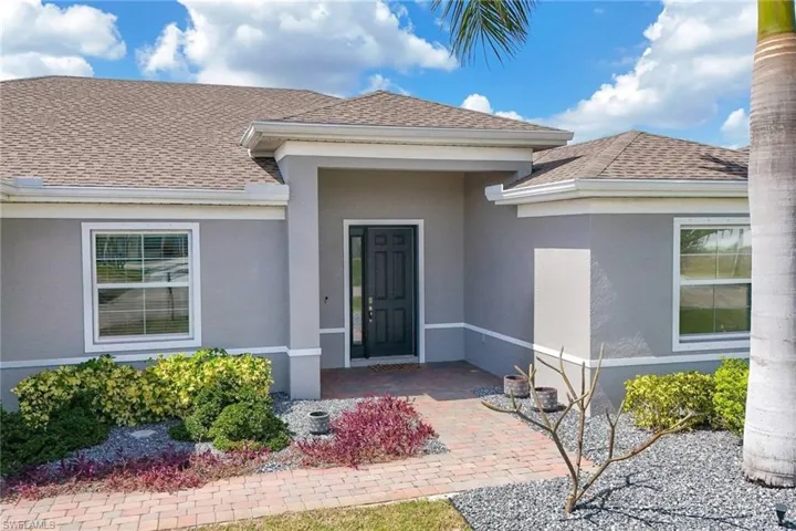 Doorway to property featuring a shingled roof and stucco