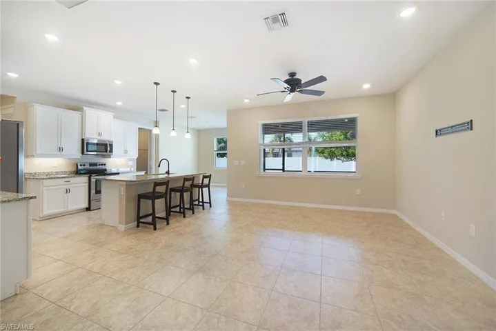 Kitchen with stainless steel appliances, pendant lighting, a kitchen breakfast bar, white cabinetry, and open floor plan