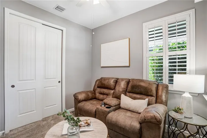 Carpeted living room with a ceiling fan and baseboards