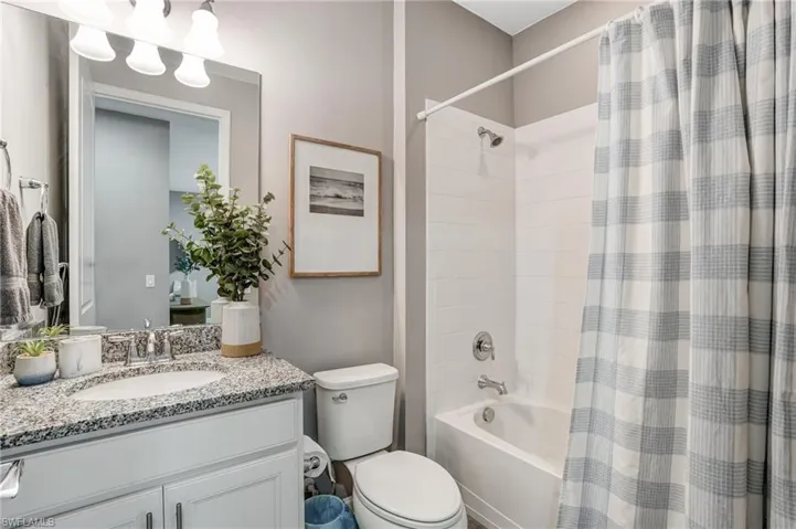 Bathroom with vanity, toilet, and shower / bath combo with shower curtain