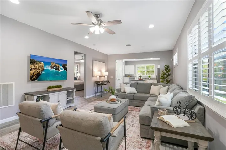 Living room with light wood-type flooring, a ceiling fan, baseboards, and recessed lighting