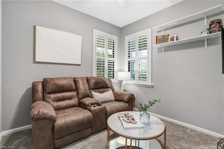 Carpeted living room featuring ceiling fan and baseboards