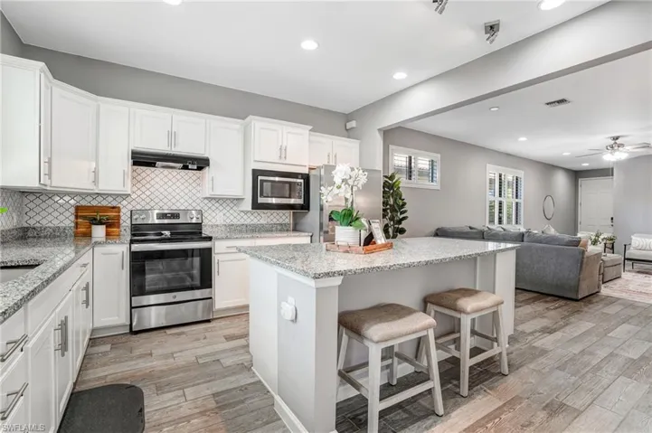 Kitchen with stainless steel appliances, recessed lighting, backsplash, light wood-style floors, and white cabinetry