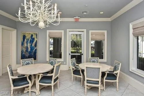 Dining area with crown molding, a chandelier, tile patterned floors, and baseboards