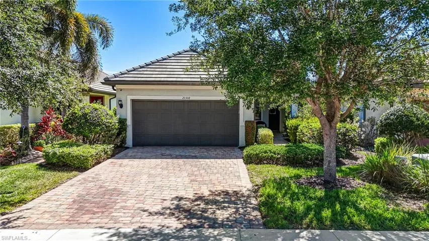 View of front of property with decorative driveway, stucco siding, an attached garage, and a tiled roof