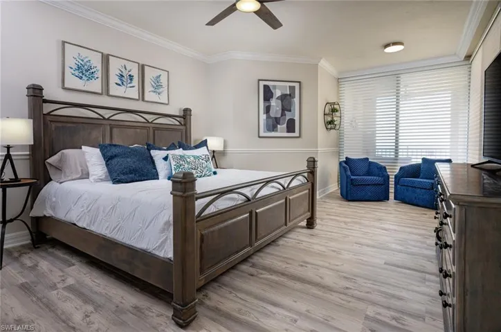 Bedroom with crown molding, light wood-style floors, and ceiling fan