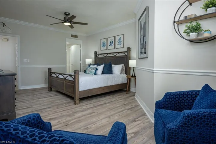 Bedroom featuring light wood finished floors, ornamental molding, and ceiling fan