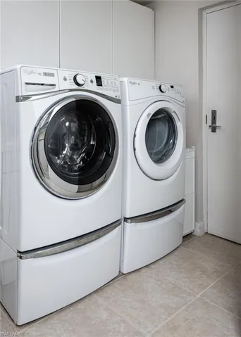 Laundry room featuring washer and dryer and light tile patterned floors