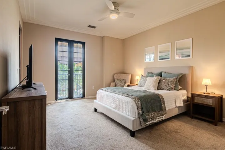 Carpeted bedroom featuring ornamental molding, ceiling fan, and french doors