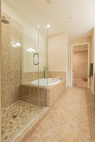 Bathroom with shower with separate bathtub and tile patterned flooring
