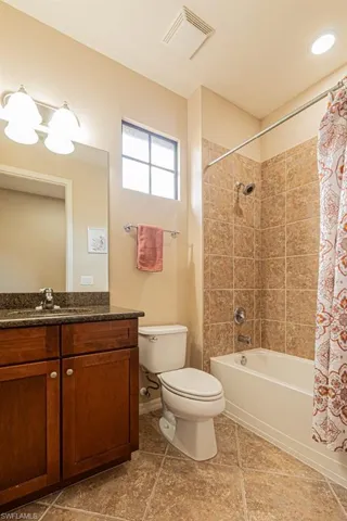 Full bathroom with vanity, shower / tub combo, tile patterned flooring, and toilet