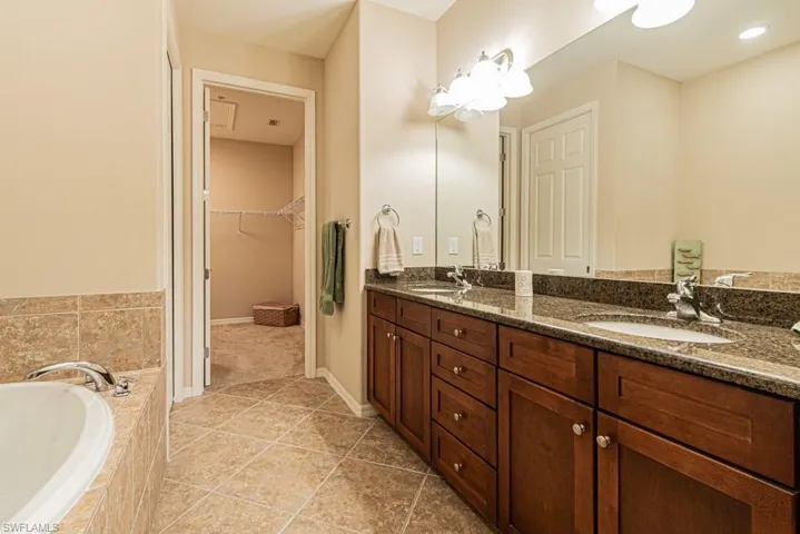 Bathroom with a relaxing tiled tub, tile patterned flooring, and double sink vanity