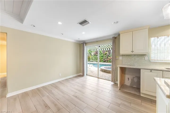 Kitchen with light wood finished floors, ornamental molding, backsplash, light stone counters, and recessed lighting