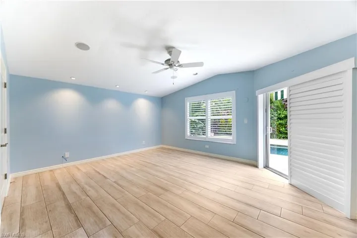 Spare room with light wood finished floors, ceiling fan, and vaulted ceiling