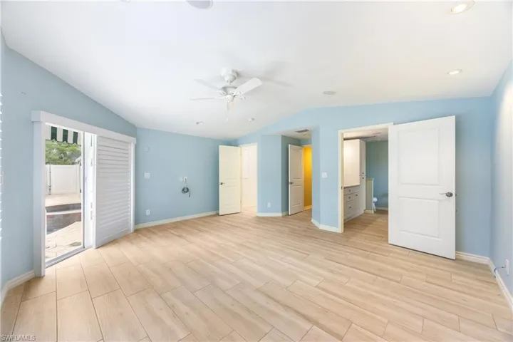 Unfurnished bedroom featuring lofted ceiling, access to exterior, light wood finished floors, and a ceiling fan
