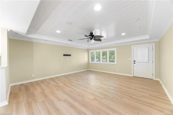 Spare room featuring ornamental molding, a raised ceiling, ceiling fan, light wood-style flooring, and recessed lighting