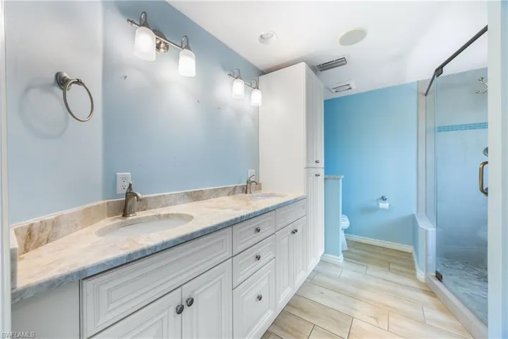 Bathroom with a stall shower, double vanity, and wood finish floors