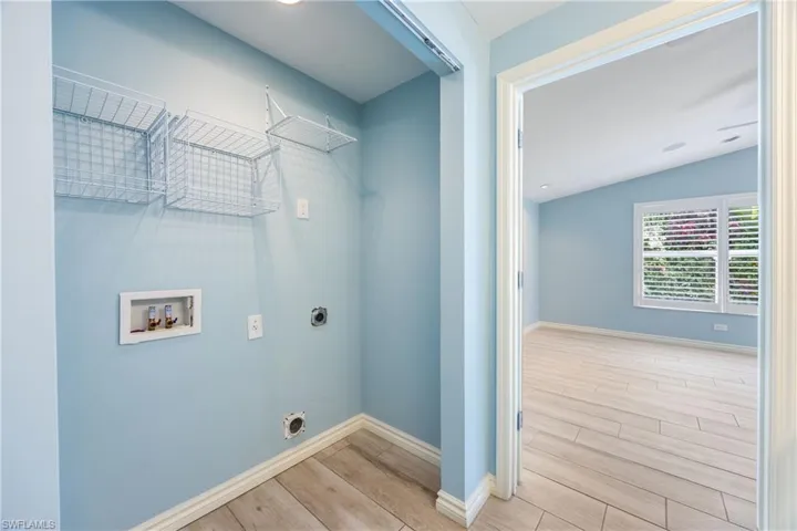 Washroom with hookup for an electric dryer, wood finished floors, and washer hookup