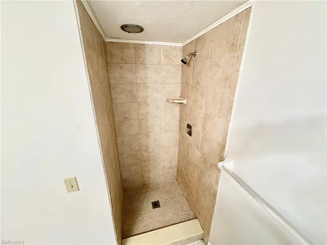 Full bathroom featuring a tile shower and ornamental molding