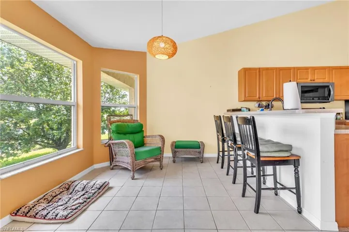 Kitchen with a breakfast bar area, baseboards, light countertops, decorative light fixtures, and light tile patterned floors