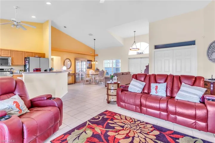 Living room with high vaulted ceiling, ceiling fan, recessed lighting, and light tile patterned floors