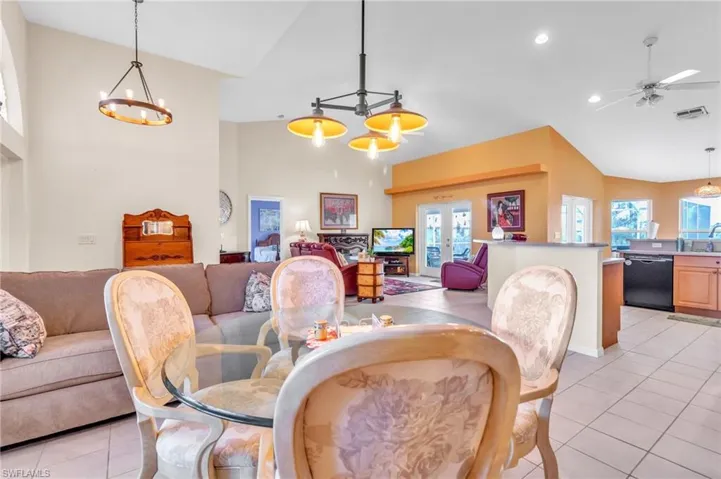 Dining space featuring light tile patterned flooring, plenty of natural light, high vaulted ceiling, and recessed lighting