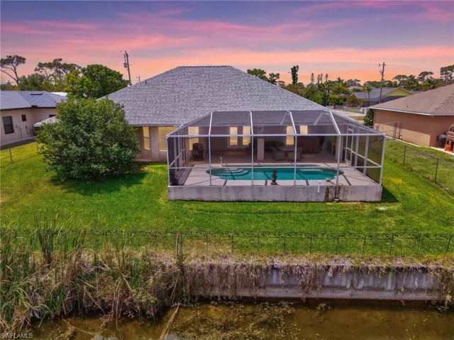 Back of property with a patio area, a lawn, a fenced backyard, and an outdoor pool