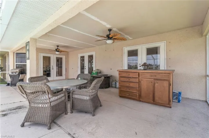 View of patio featuring grilling area, outdoor dining space, ceiling fan, and french doors