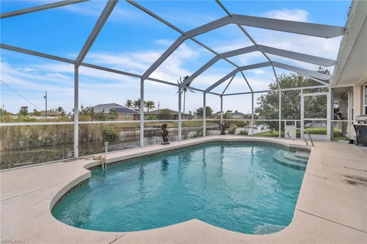 Outdoor pool with glass enclosure, a patio, and a water view