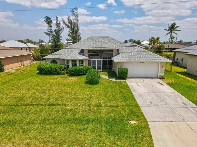 Ranch-style home featuring a shingled roof, stucco siding, driveway, a front yard, and a garage