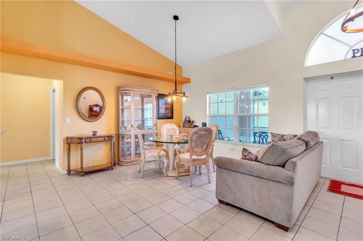 Dining space with high vaulted ceiling, baseboards, and light tile patterned floors