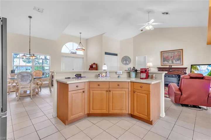 Kitchen with light countertops, visible vents, high vaulted ceiling, and ceiling fan