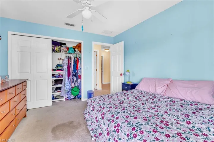 Bedroom with a closet, visible vents, light colored carpet, and ceiling fan
