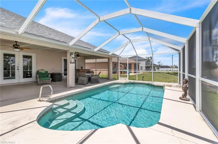Pool with glass enclosure, a ceiling fan, french doors, and a patio