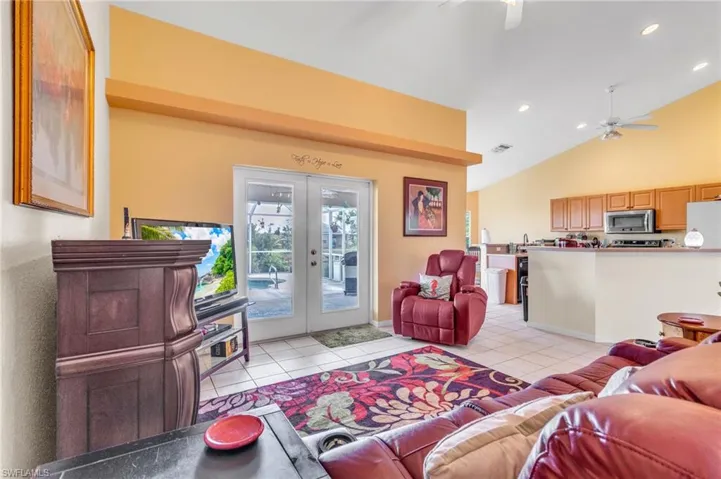 Living area featuring french doors, visible vents, lofted ceiling, a ceiling fan, and light tile patterned floors