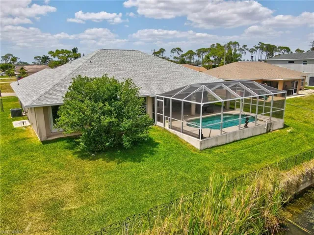 Back of property with a yard, roof with shingles, and an outdoor pool