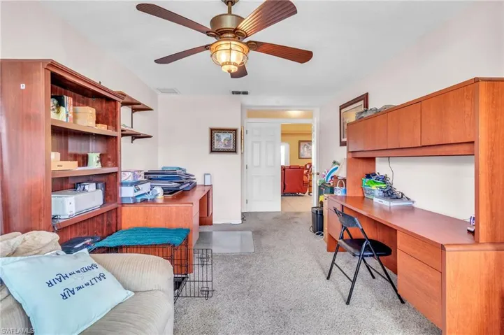 Office with light carpet, a ceiling fan, and visible vents